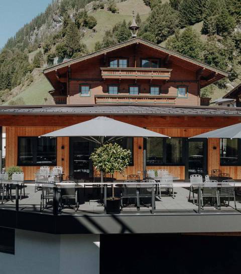 Modern renovierte Sonnenterrasse des Familienhotel Oberkarteis mit Sitzplätzen und Sonnenschirmen vor alpiner Bergkulisse