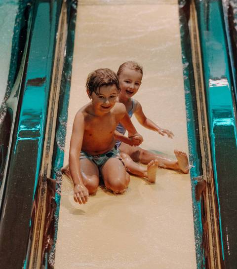 Kinder rutschen lachend eine Wasserrutsche in der Wasserwelt im Großarltal hinunter