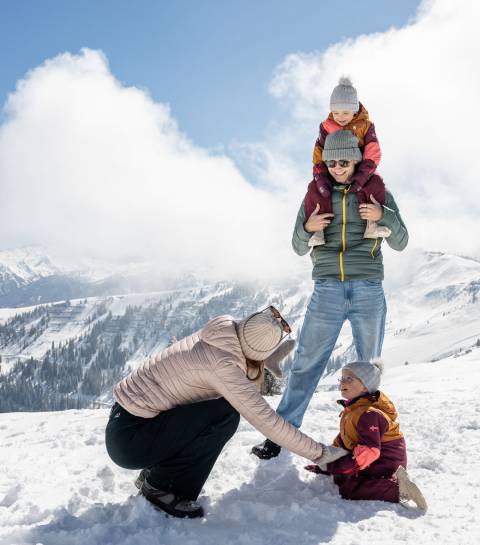 Eltern und Kinder spielen im Schnee in der alpinen Bergwelt