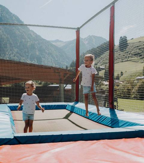 Zwei Mädchen auf dem Trampolin auf dem Abenteuerspielplatz des Hotels
