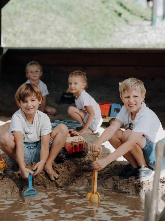 Kinder spielen im Wasser- und Sandbereich der Outdoor-Spielwelt im Familienhotel Oberkarteis
