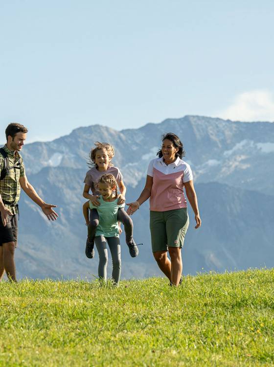 Eltern und Kinder bei Wanderung über grüne Almwiesen im Großarltal.