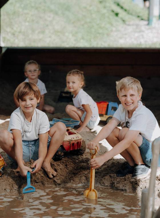 Kinder spielen im Wasser- und Sandbereich der Outdoor-Spielwelt im Familienhotel Oberkarteis