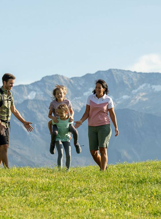 Eltern und Kinder bei Wanderung über grüne Almwiesen im Großarltal.