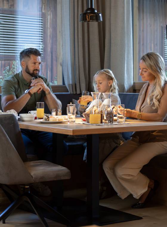 Familie beim gemeinsamen Frühstück mit Orangensaft am gedeckten Tisch im Familienhotel Oberkarteis