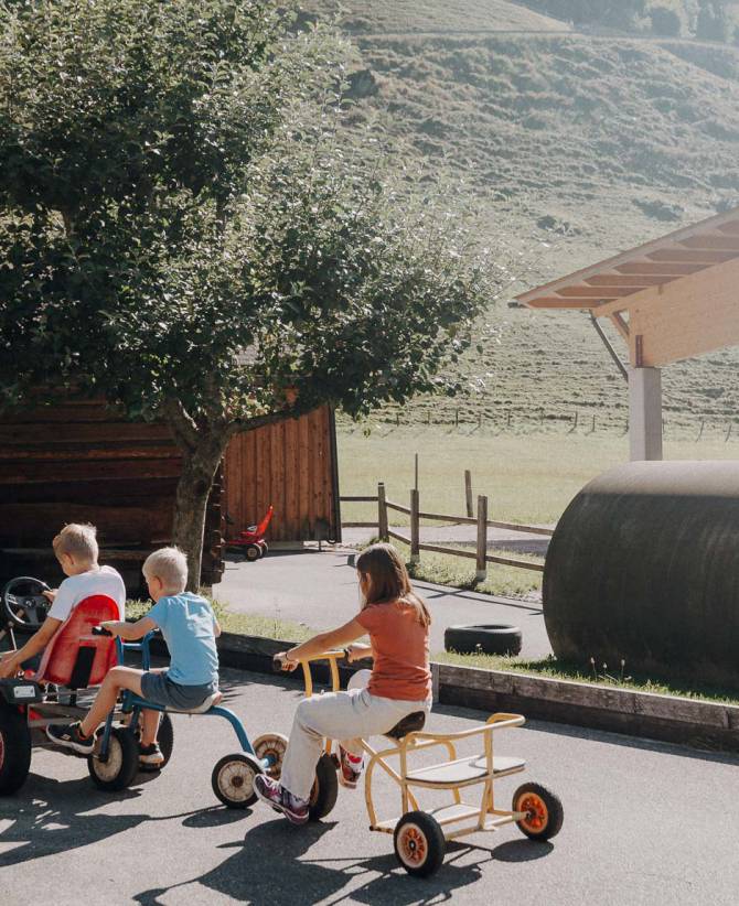 Kinder fahren Dreirad und Bobbycar auf dem Spielareal im Familienhotel Oberkarteis