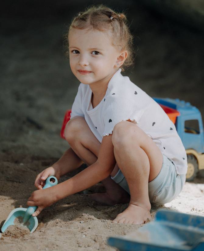 Lächelndes Mädchen beim Spielen im Sandbereich der Spielwelt im Familienhotel Oberkarteis
