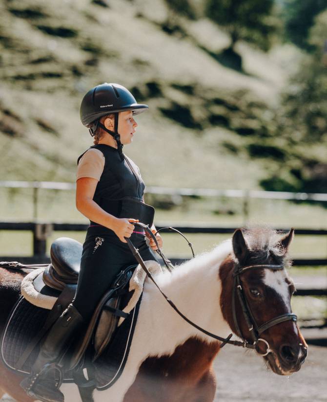 Mädchen im Trab auf einem Pony im Familienhotel Oberkarteis – sicheres Kinderreiten im Familienurlaub