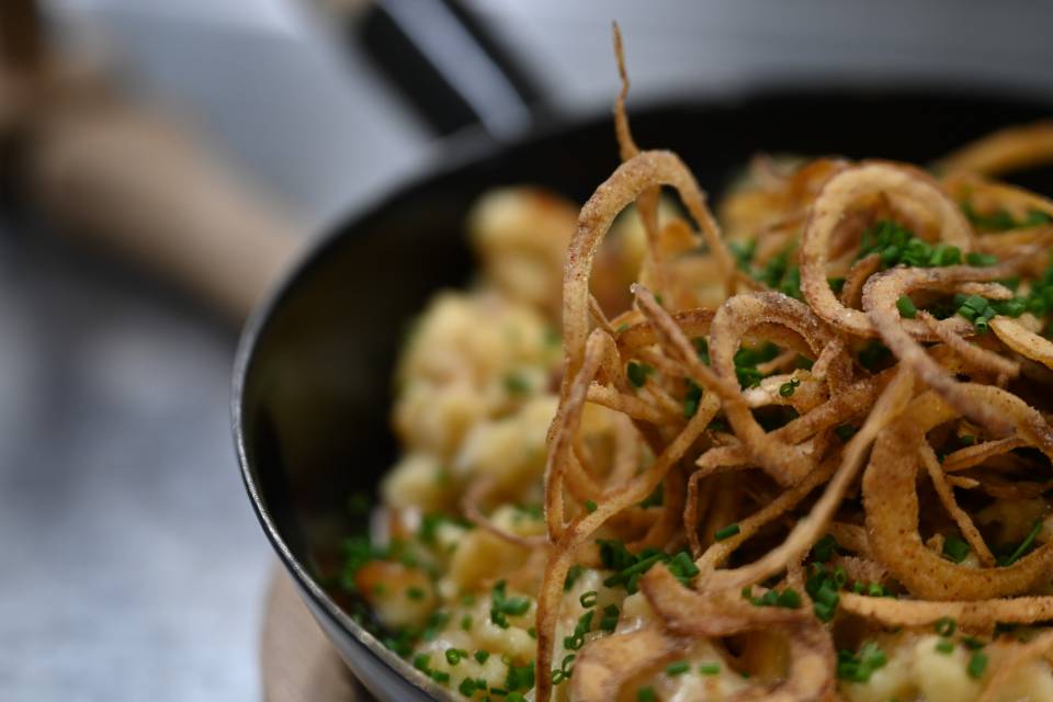 Hausgemachte Käsespätzle mit knusprigen Röstzwiebeln als regionale Spezialität im Hotel Oberkarteis