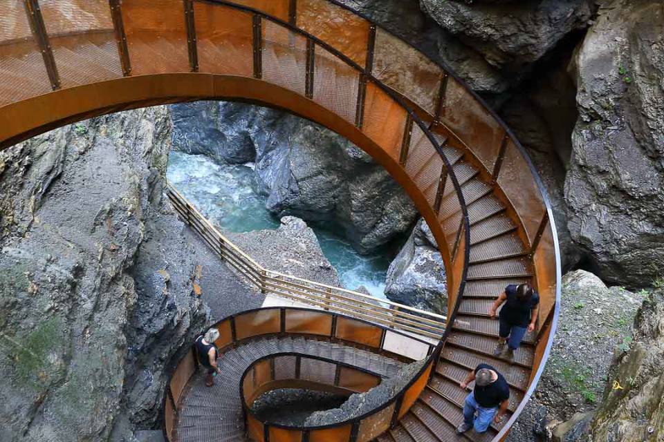 Geschwungene Metalltreppe führt spiralförmig durch eine enge Felsklamm über türkisfarbenem Wasser – Naturausflug beim Familienhotel Oberkarteis