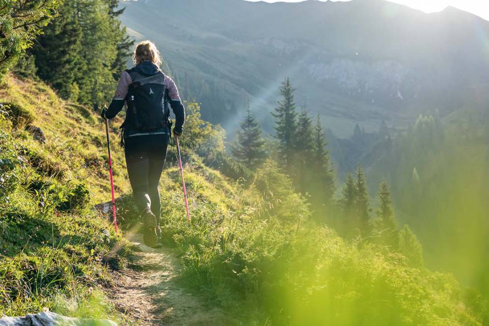 Wanderin mit Stöcken auf einem sonnigen Bergpfad in den Alpen nahe dem Familienhotel Oberkarteis