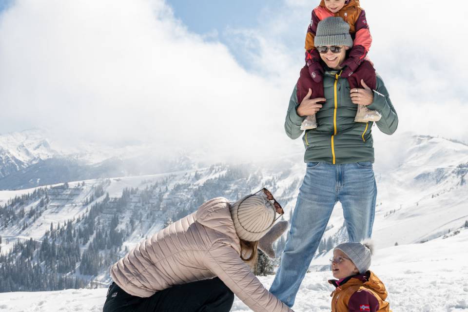 Eltern und Kinder spielen im Schnee in der alpinen Bergwelt