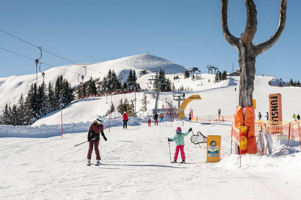 Skifahrer beim Skifahren auf sonniger Skipiste mit Panorama auf die verschneite Bergwelt