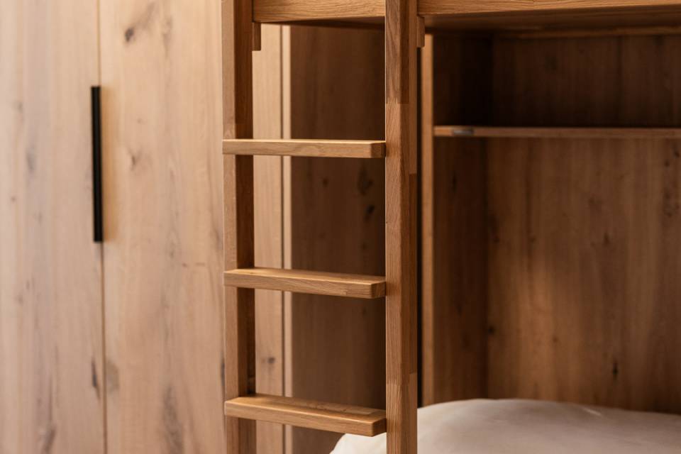 Stockbett aus Holz mit Leiter und Kleiderschrank im Familienzimmer im Hotel Oberkarteis