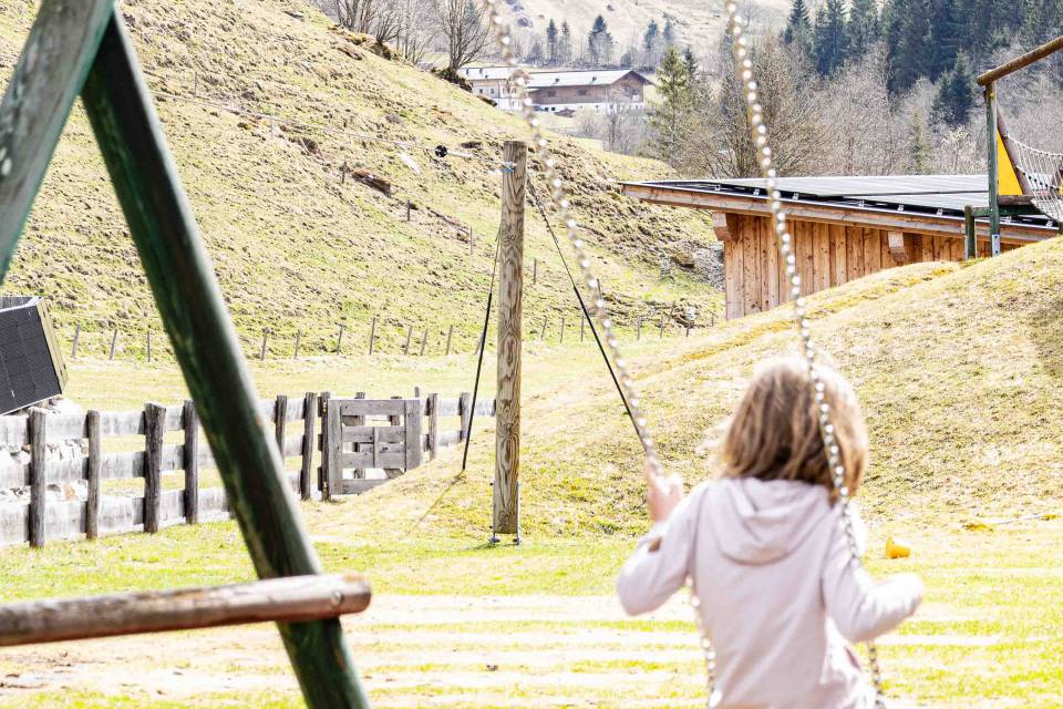 Mädchen auf der Schaukel am Außenspielplatz des Familienhotels Oberkarteis