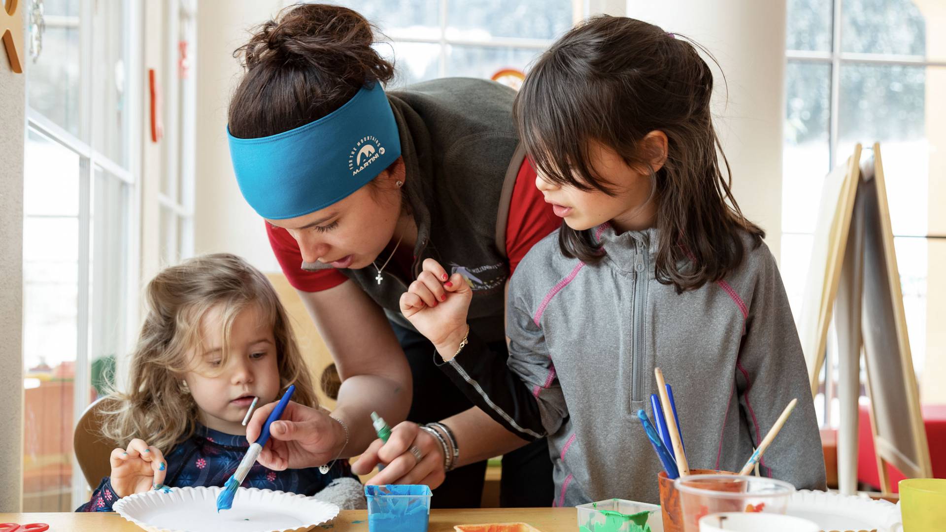 Kinder malen mit Betreuerin im Kreativraum der Kinderbetreuung im Familienhotel Oberkarteis