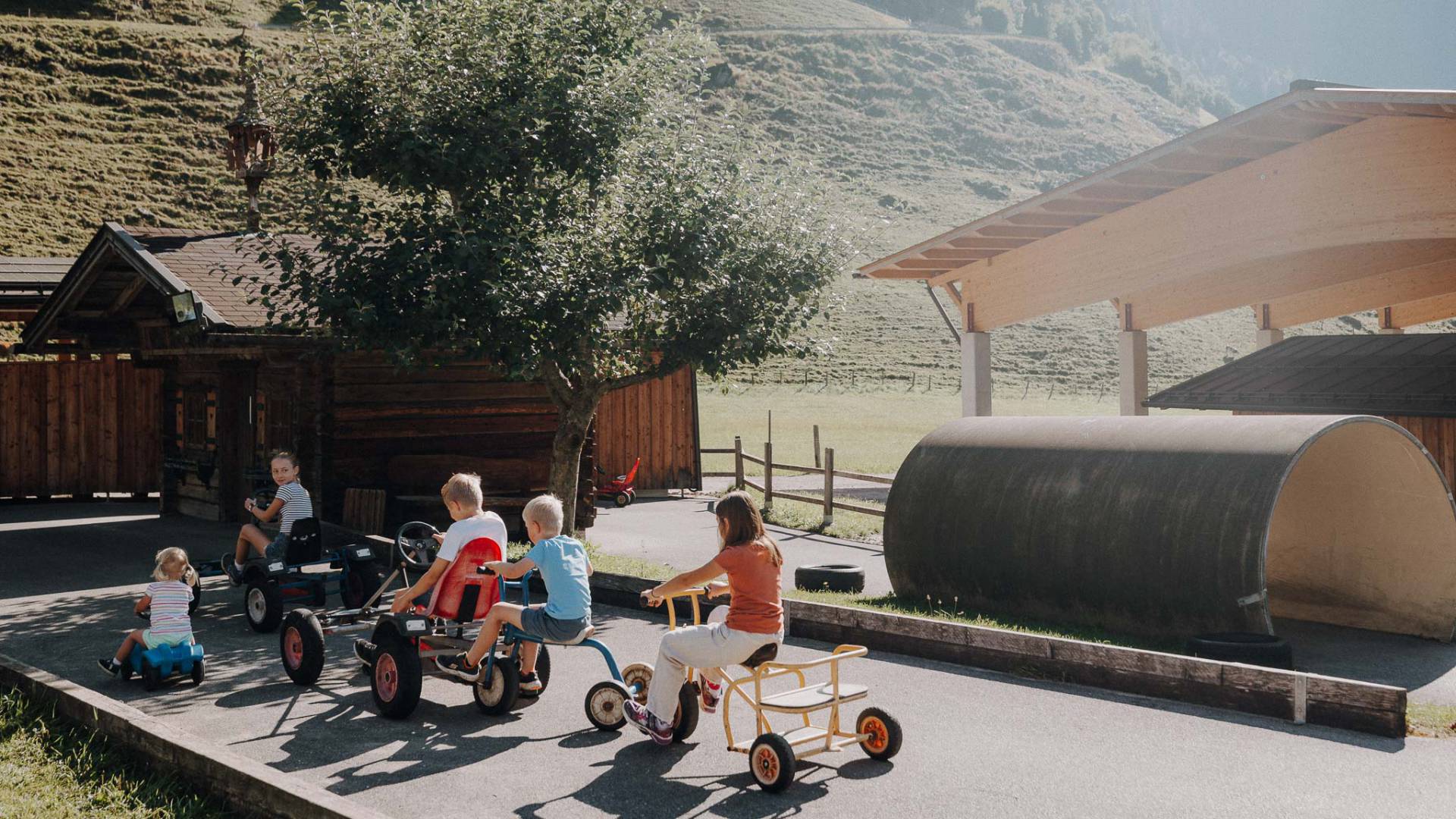 Kinder fahren Dreirad und Bobbycar auf dem Spielareal im Familienhotel Oberkarteis