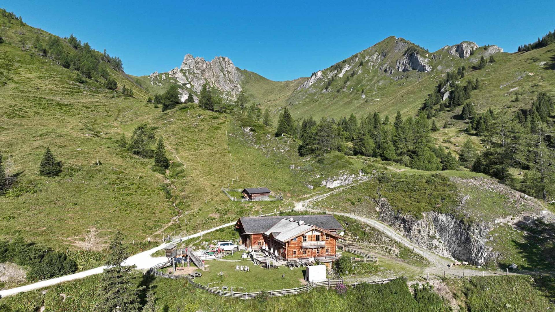 Luftaufnahme einer Alm in den Salzburger Bergen mit grüner Bergwelt und Wanderwegen im Sommer