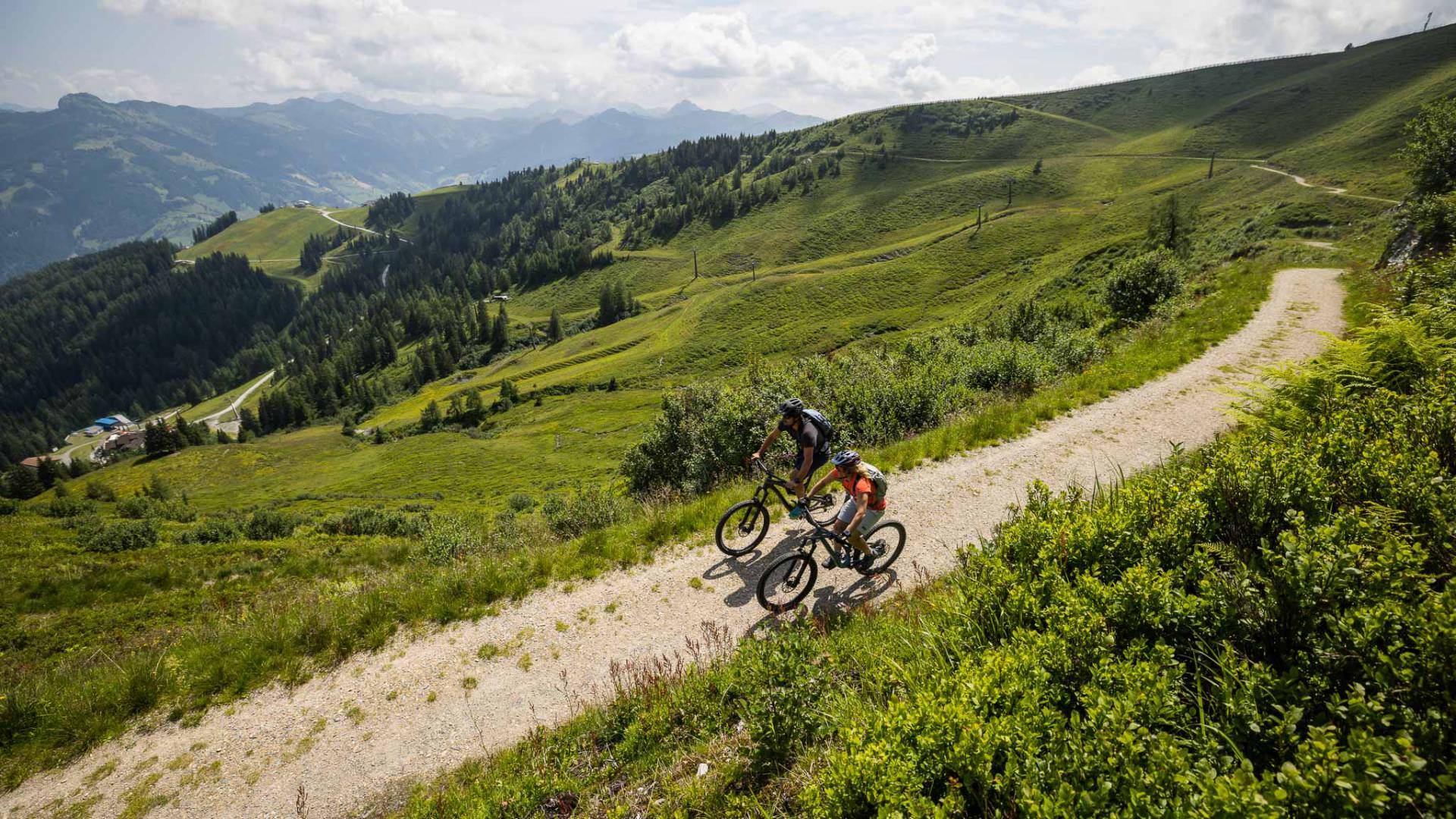 Mountainbiker auf Panoramaweg durch grüne Almwiesen in der Bergwelt im Salzburger Land