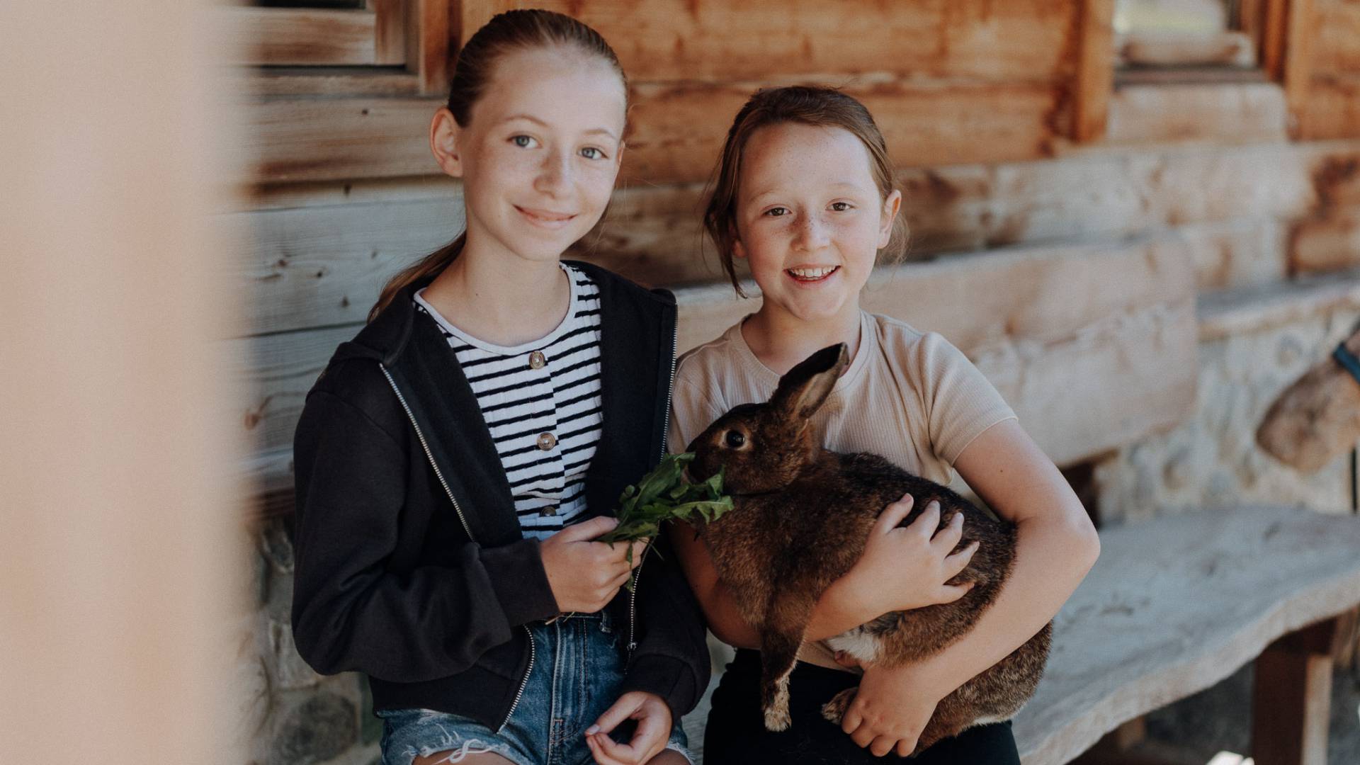 Zwei Mädchen mit Hase im Stall am Kinderbauernhof Oberkarteis in Salzburg