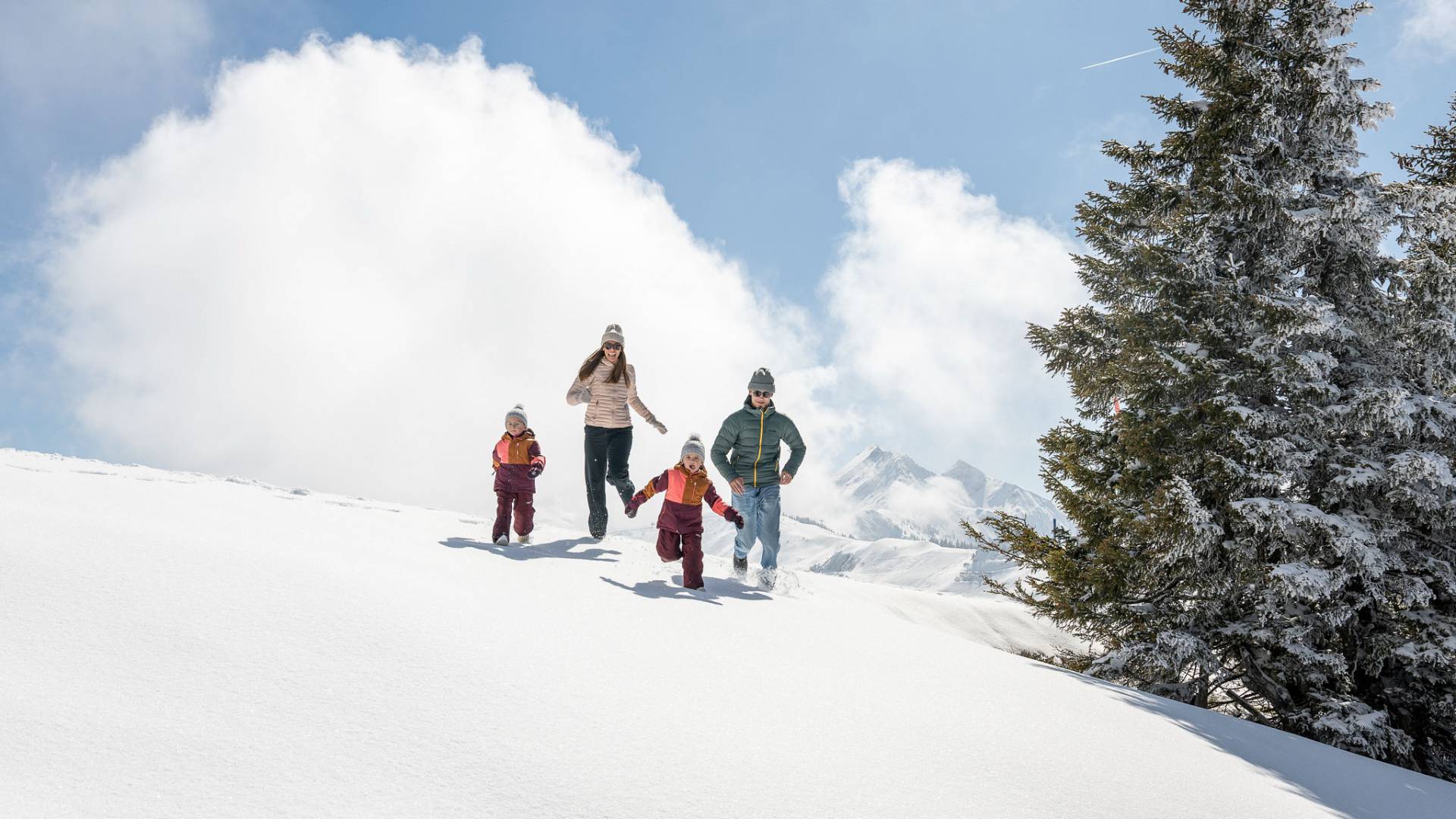 Winterurlaub mit Kindern: Familie spielt gemeinsam im frischen Pulverschnee