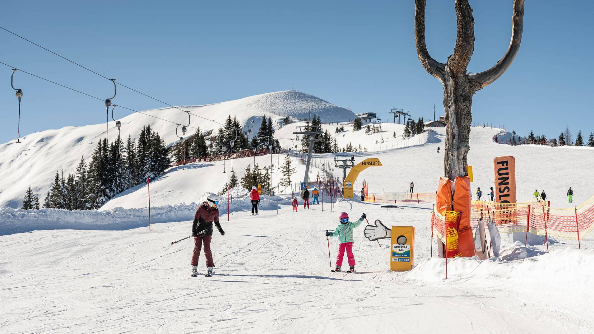 Skifahrer beim Skifahren auf sonniger Skipiste mit Panorama auf die verschneite Bergwelt