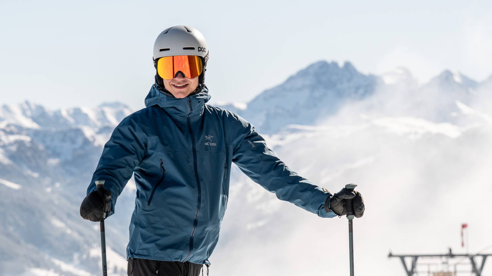 Skifahrer mit Helm und Skibrille vor beeindruckender Winterkulisse in den Alpen