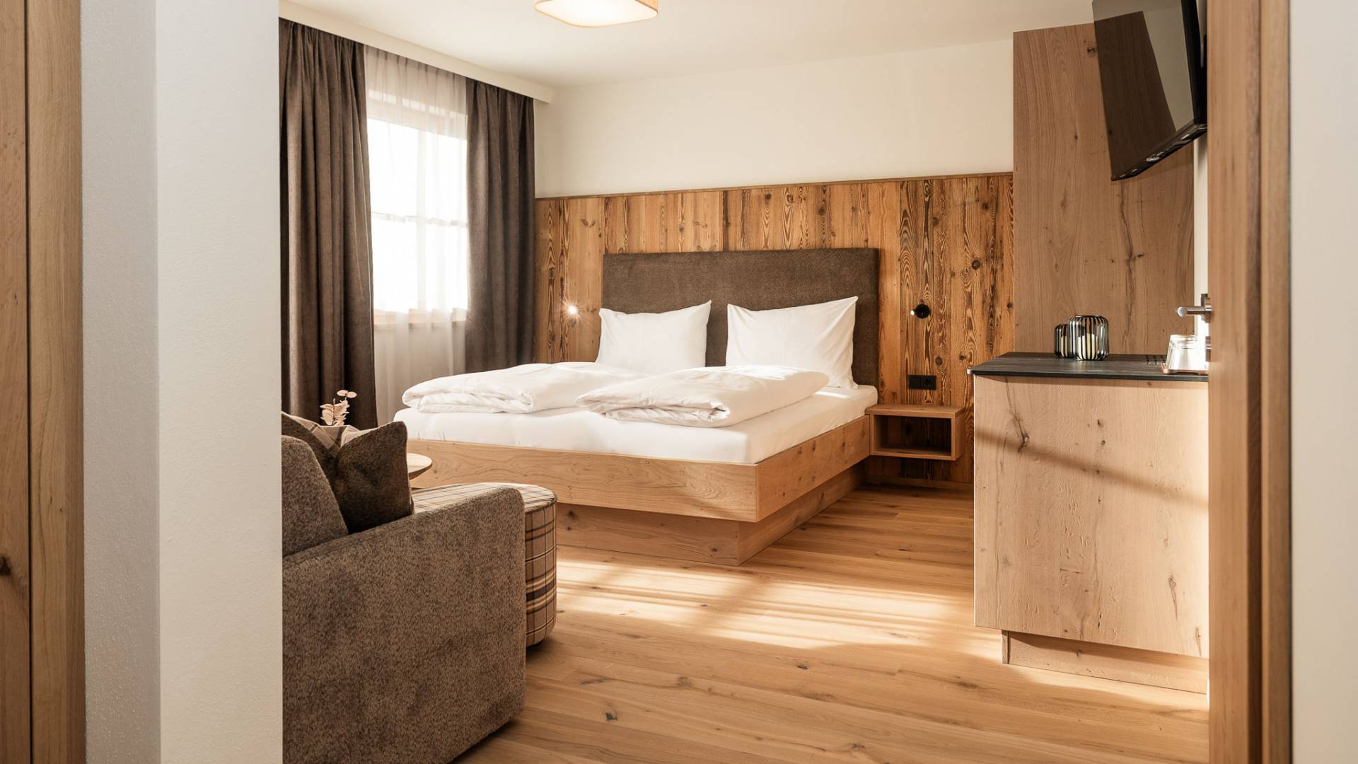 Doppelbett und Couch im großzügigen Familienzimmer des Familienhotels Oberkarteis