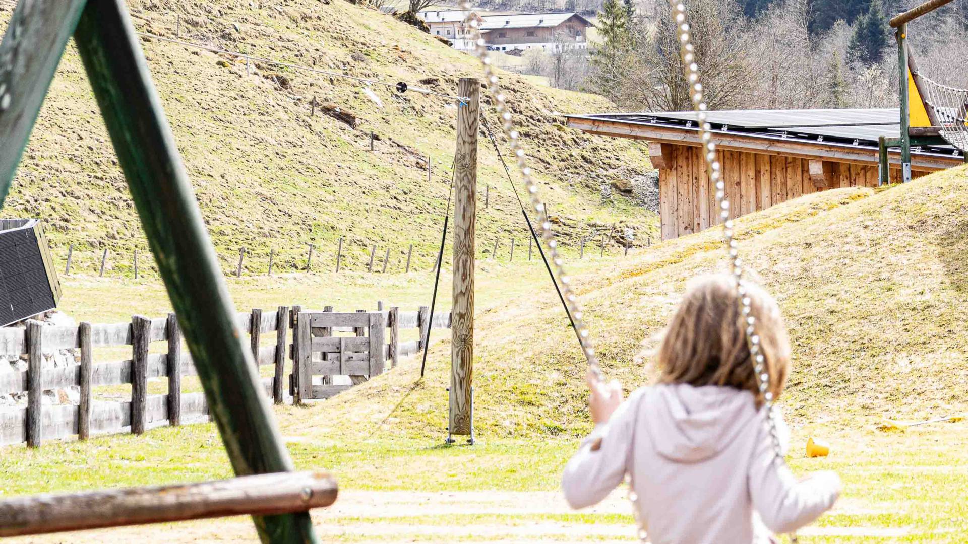 Mädchen auf der Schaukel am Außenspielplatz des Familienhotels Oberkarteis
