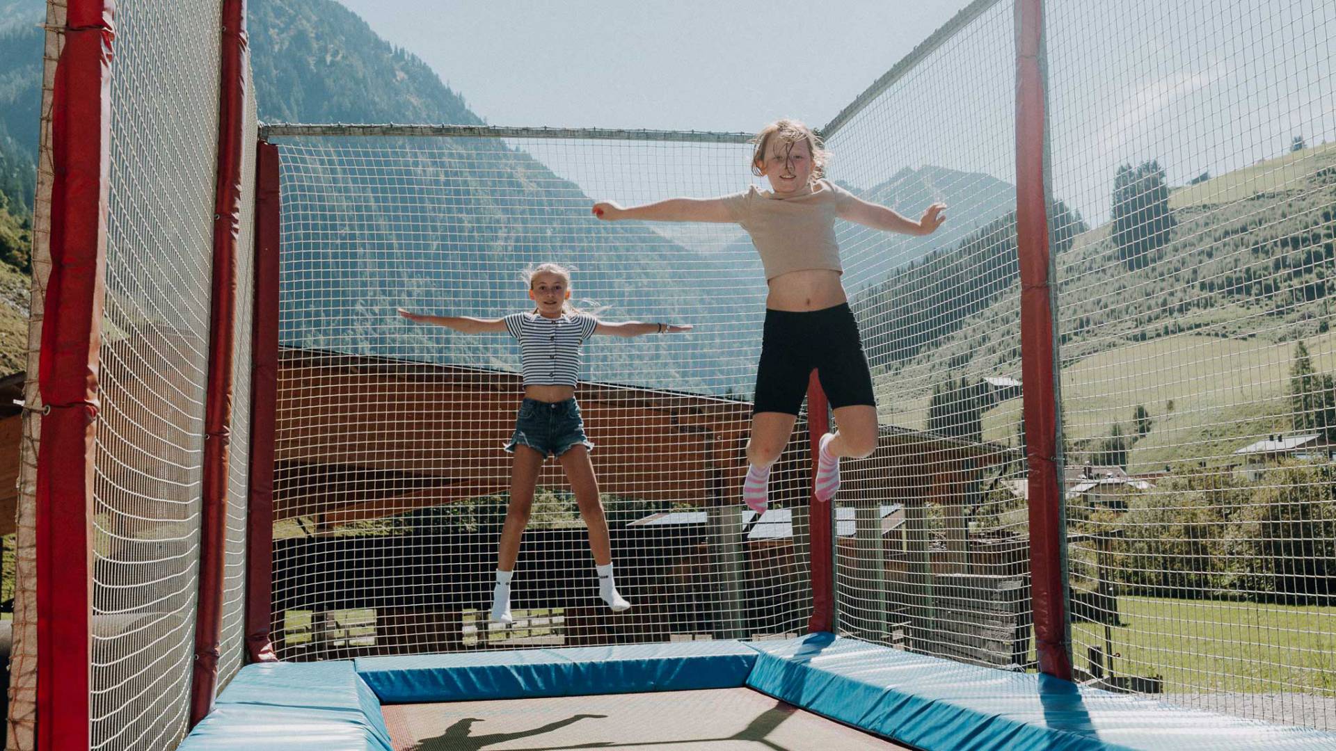Kinder springen auf dem Trampolin im Outdoor-Spielbereich des Familienhotels Oberkarteis