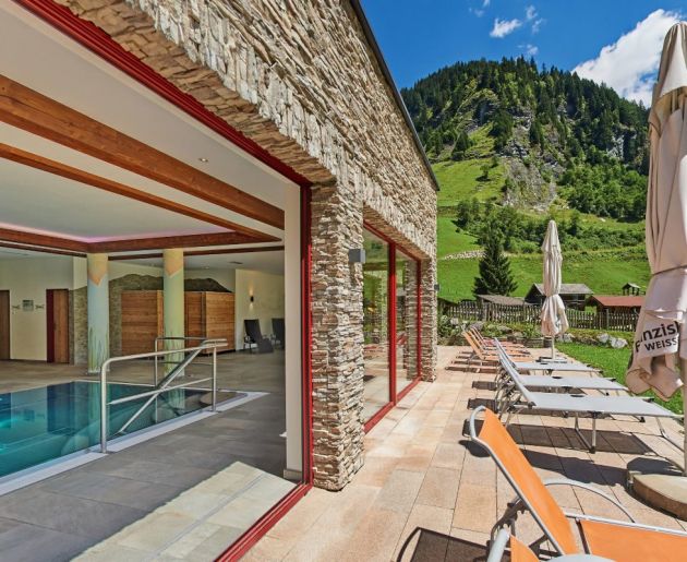Geöffnete Glasfront vom Hallenbad zur Panoramaterrasse mit Liegewiese